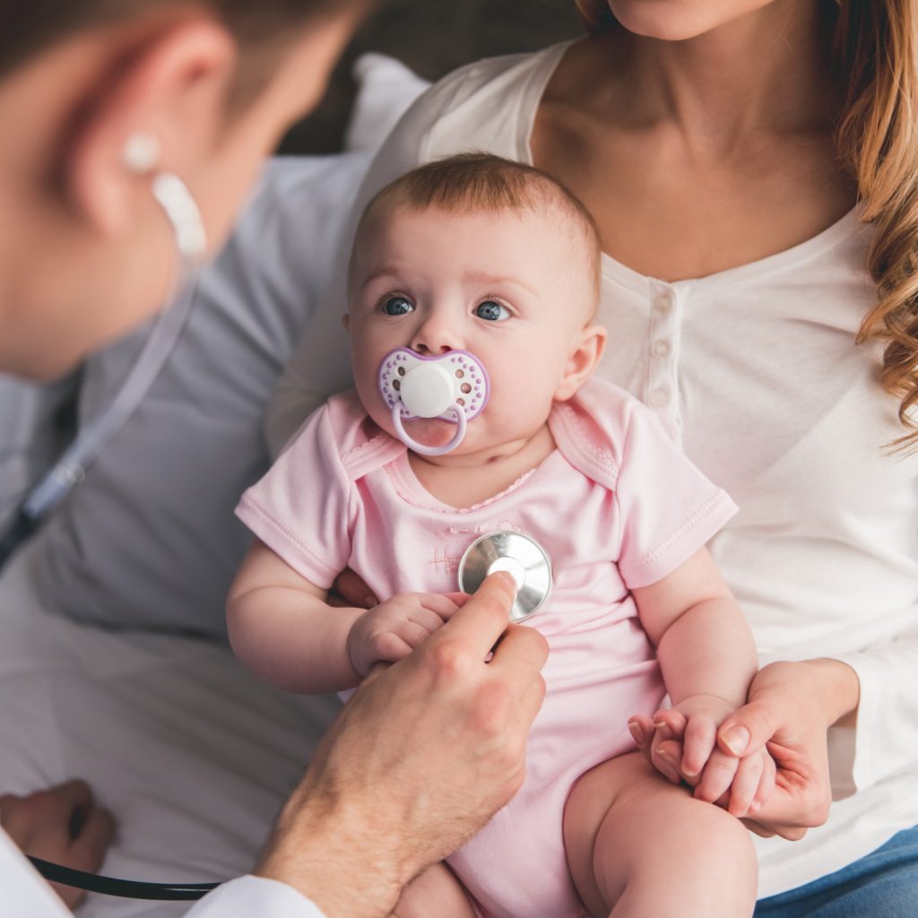 A pediatrician examining a baby girl